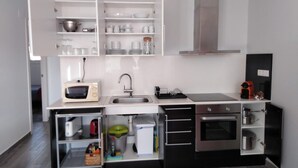 Eine moderne Küche mit weißen Schränken, einer Mikrowelle, einem Spülbecken, einem Herd und einer Kaffeemaschine.