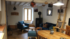 A cozy living room with a wooden dining table, blue sofas, and a fireplace. - In the heart of a preserved, welcoming, flower-filled mountain village (La Fajolle)