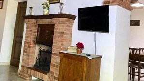 Un saló amb una llar de pedra, un armari de fusta i un televisor de pantalla plana fixat a la paret.