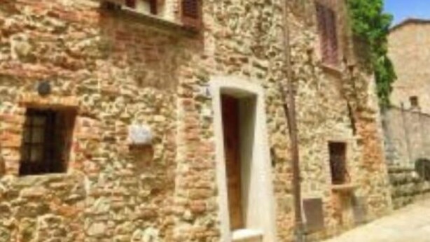 Edifici de pedra amb disseny tradicional, que presenta una petita entrada i finestres amb persianes.