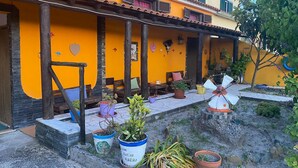 Un edificio con fachada amarilla, mesas al aire libre y plantas en macetas.