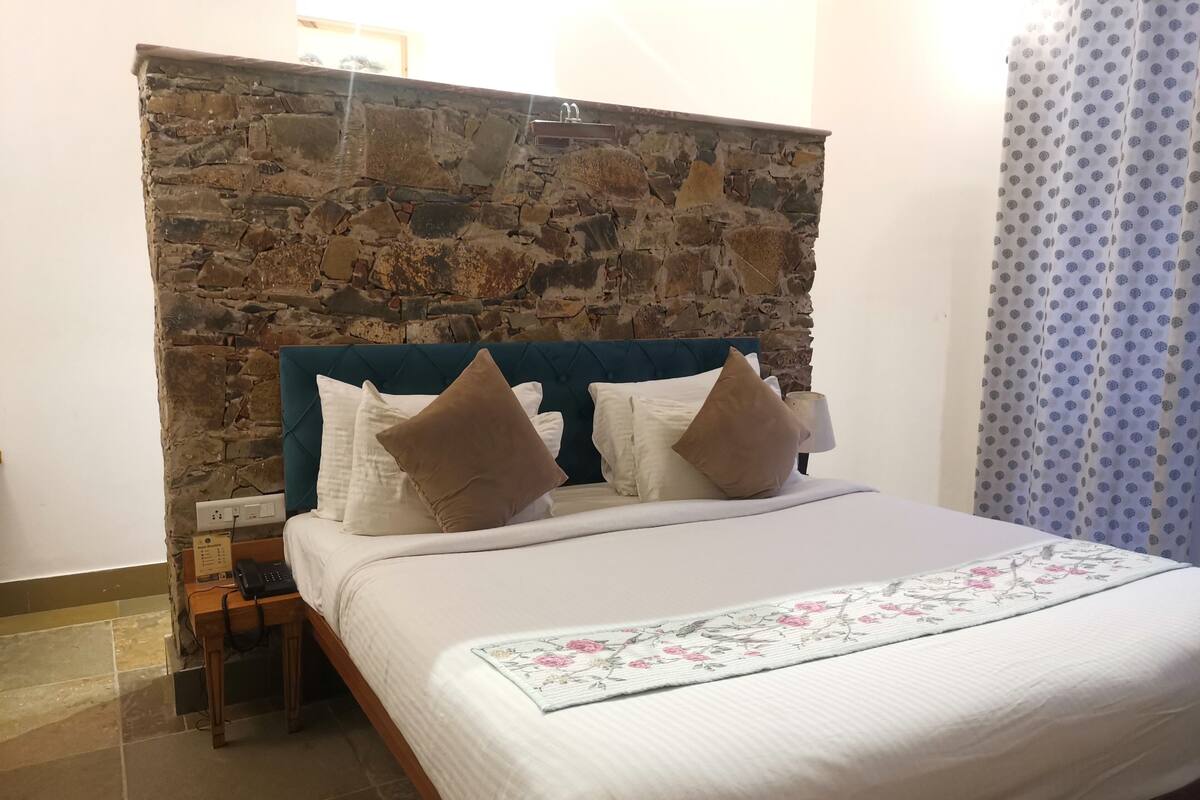 Ein Bett mit steinernen Kopfteil, weißer Bettwäsche und einer Decke mit Blumenmuster.