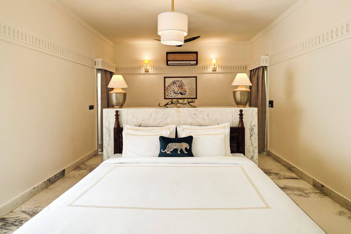 Ein Hotelzimmer mit einem großen Bett, zwei Nachttischlampen, einem Deckenventilator und einem gerahmten Kunstwerk an der Wand.