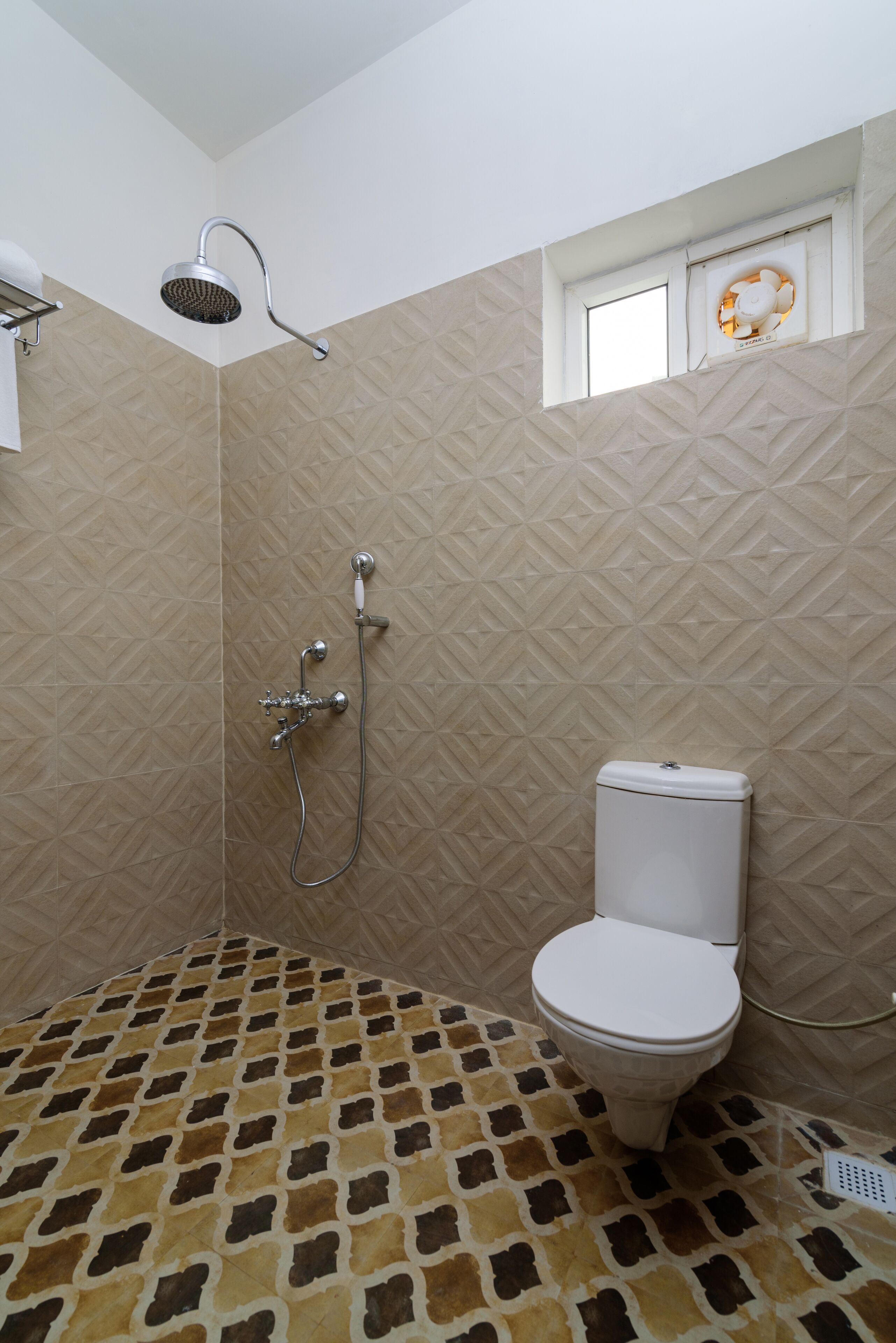 Une salle de bain avec douche, toilettes et carrelage décoratif.