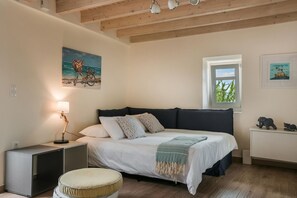 Quarto com cama, abajur, obra de arte, janela e um pequeno armário.