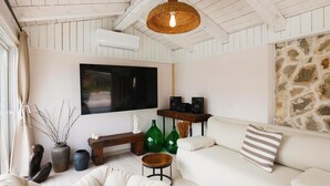 Een gezellige woonkamer met een witte bank, een televisie en een stenen muur.