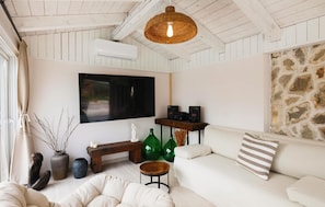 A cozy living room with a white sofa, a television, and a stone wall. - Amazing home in Posedarje (Posedarje)