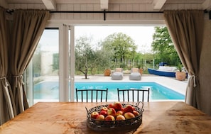 A wooden table with a fruit bowl, a pool, and outdoor seating. - Amazing home in Posedarje (Posedarje)