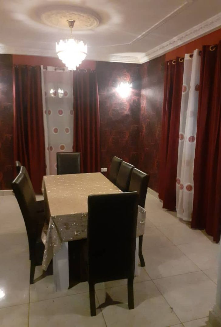 A dining area with a rectangular table, six chairs, and a chandelier.
