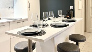A modern kitchen with a central island, bar stools, and a black accent wall. - Charming T2 with terrace and private parking (Champagne-au-Mont-d'Or)