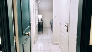 A hallway with white tiled flooring, a ceiling light fixture, and closed doors on both sides. - Charming T2 with terrace and private parking (Champagne-au-Mont-d'Or)