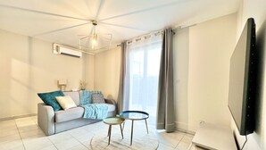 A modern living room with a sofa, a coffee table, and a flat-screen TV mounted on the wall. - Charming T2 with terrace and private parking (Champagne-au-Mont-d'Or)