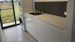 A compact kitchen with a built-in washing machine, a sink, and a view of the outdoors. - The Farm. Entire house country stay (Applethorpe)