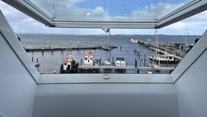 Une vue depuis une fenêtre donnant sur une marina où plusieurs bateaux sont amarrés au quai.
