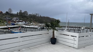 Une promenade en bord de mer agrémentée de palmiers, un quai avec des bateaux et une vue sur la mer.