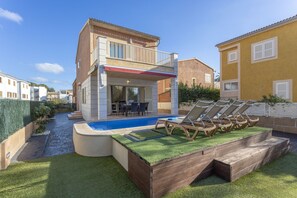 A two-story house with a balcony, a swimming pool, and outdoor seating.