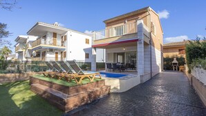 A two-story house with a swimming pool, outdoor seating, and a barbecue area.