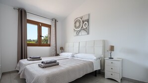 Un dormitorio con dos camas, una ventana con cortinas, una mesita de noche con lámpara y una obra de arte abstracto colgada en la pared.