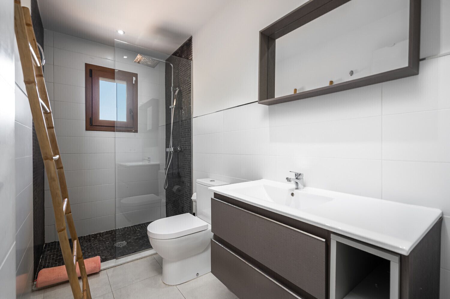 Uma casa de banho moderna com chuveiro, sanita e lavatório.
