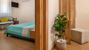 A bedroom with a bed, bedside table, lamp, and a potted plant. - Diogenis House (Zakynthos)