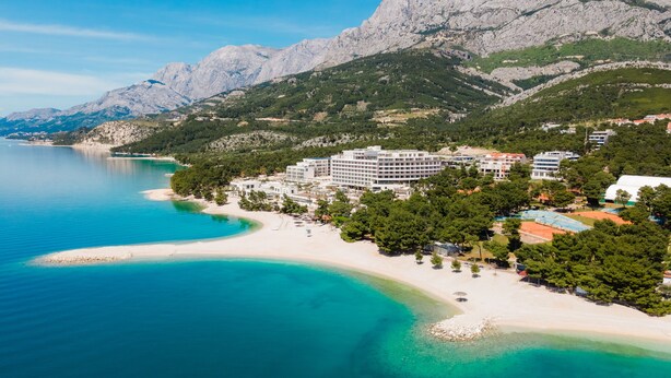 A coastal hotel with a beach, mountains, and clear blue waters. - Sun Spalato Villa Ivano (Makarska)