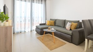 A modern living room with a grey sofa, a small round table, and a large window with sheer curtains. - Sun Spalato Villa Ivano (Makarska)