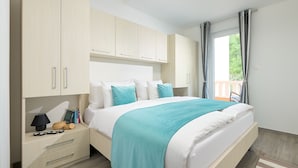 A modern bedroom with a bed, a nightstand, and a view of the outdoors through a window. - Sun Spalato Villa Ivano (Makarska)