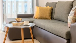 A modern living room with a grey sofa, a small round table with a bowl of cookies and a cup, and a woven rug. - Sun Spalato Villa Ivano (Makarska)