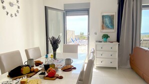 Un área de comedor con una mesa lista para el desayuno, que incluye pan, queso y un jarrón con flores.