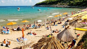 Una playa con tumbonas, sombrillas y gente relajándose.