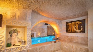 A stone interior with a pool, a statue, and an archway.