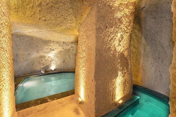 Un espacio de spa con piscina, paredes de piedra e iluminación integrada.