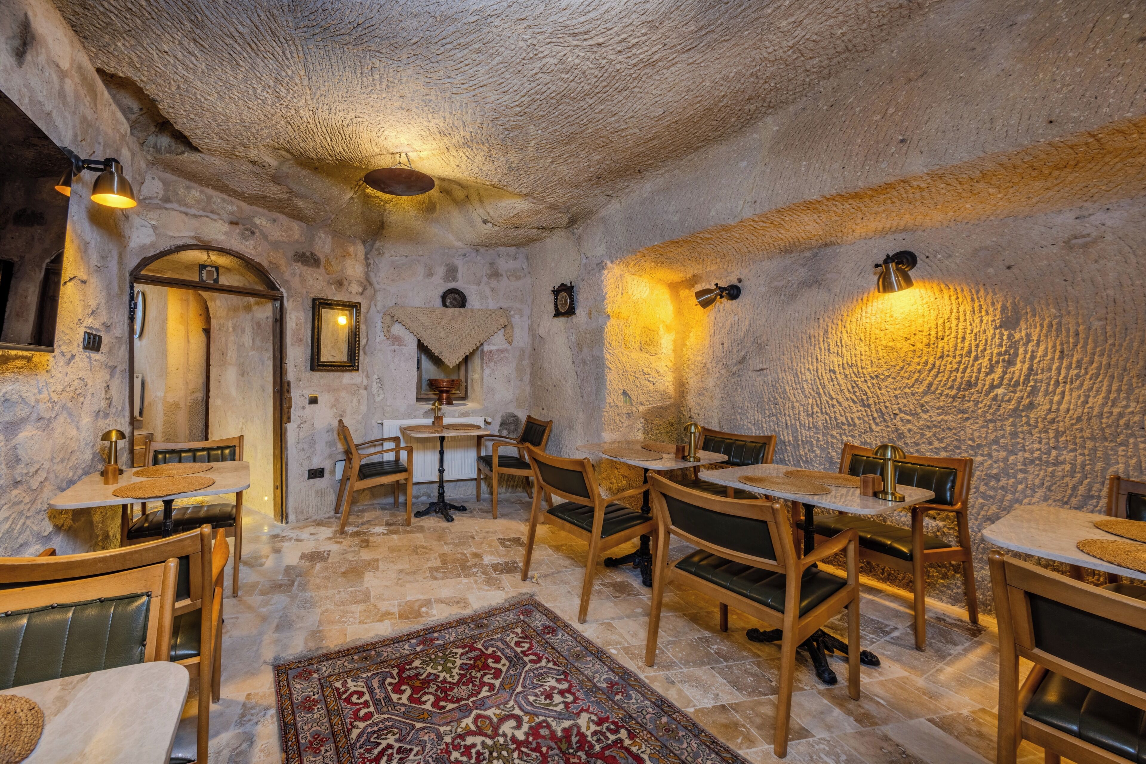 A rustic interior with stone walls, wooden furniture, and a patterned rug.