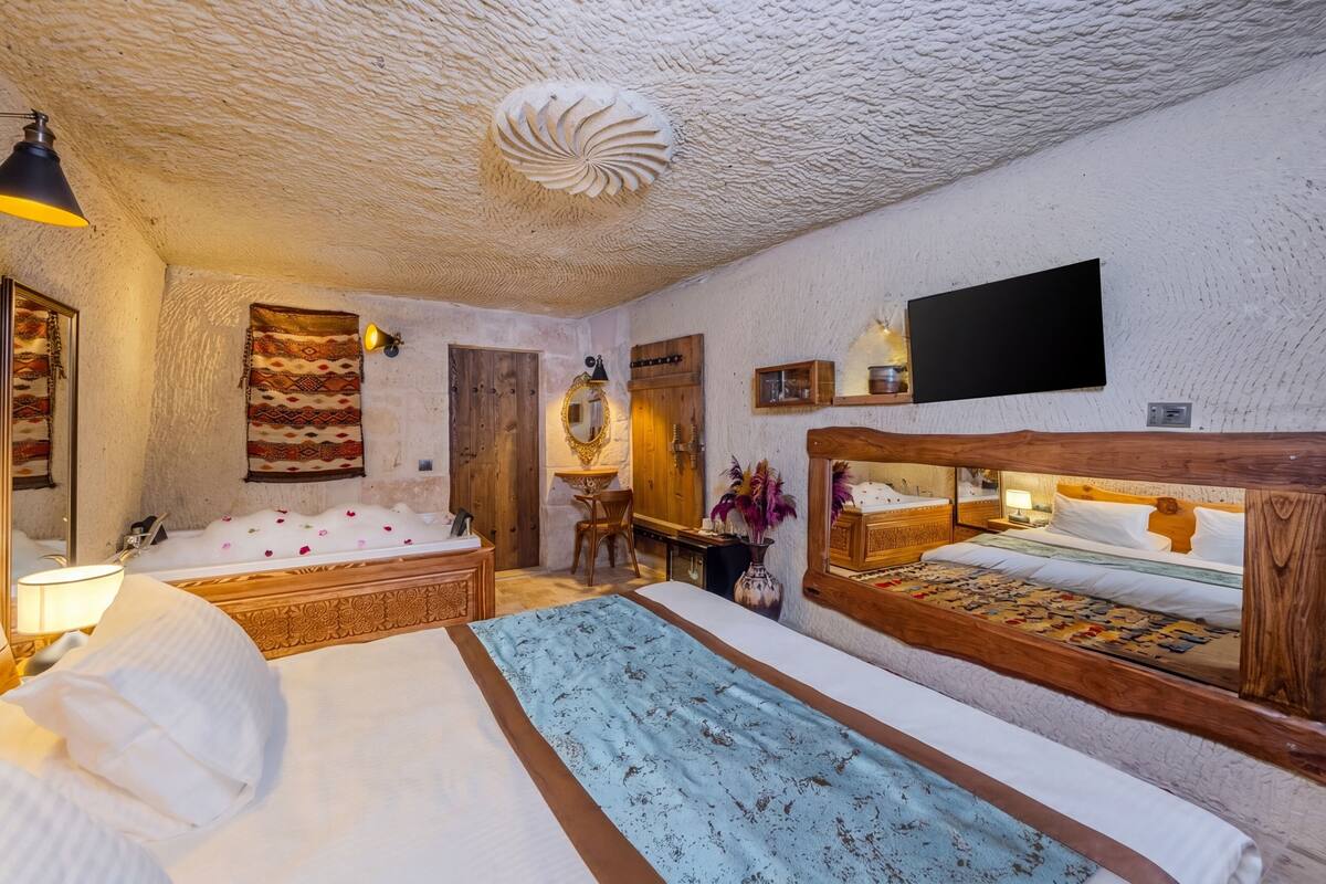 Ein Zimmer mit zwei Betten, einem Holzkopfende, einem Spiegel, einem Flachbildfernseher und einer strukturierten Decke.