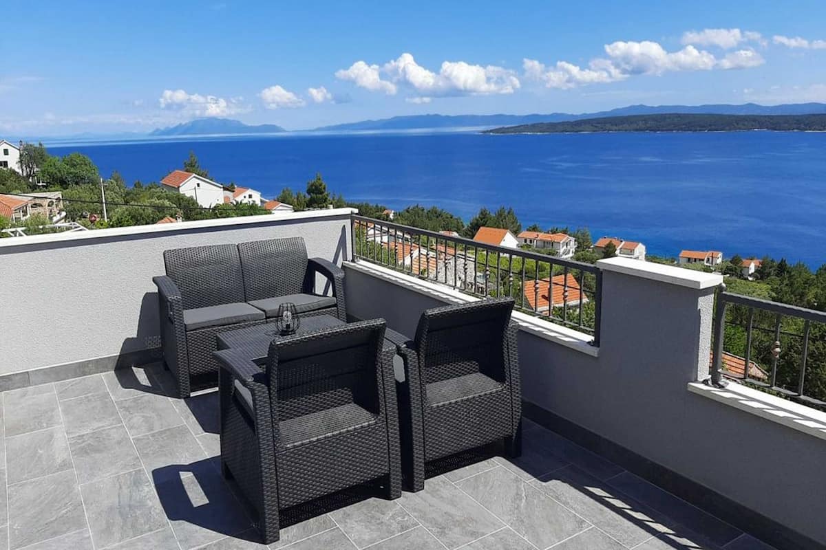 A terrace with wicker furniture and a view of the sea.