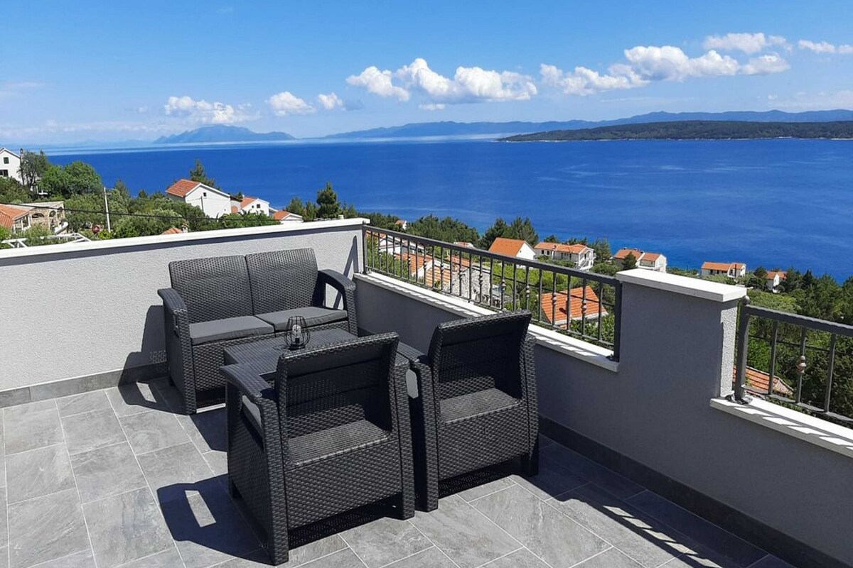 A terrace with wicker furniture and a view of the sea.