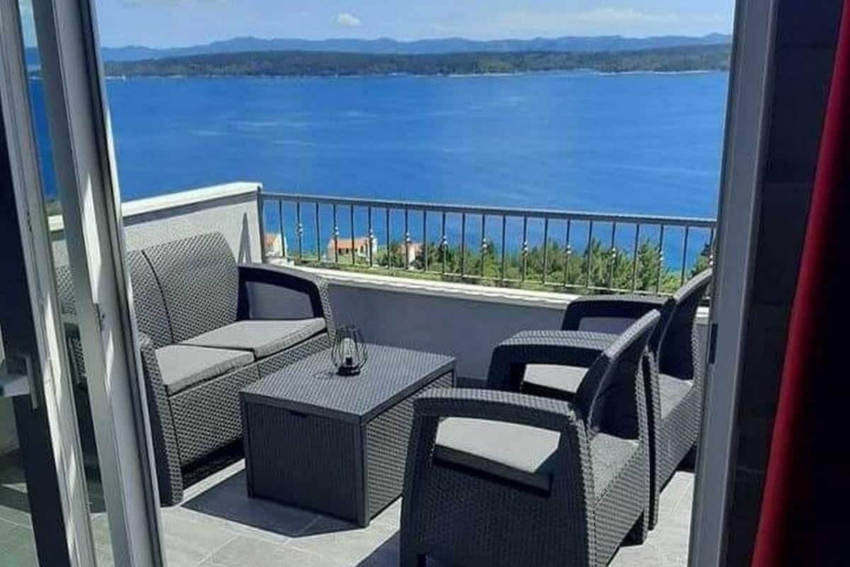 A balcony with wicker furniture and a view of a large body of water.