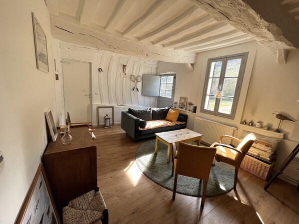 Un salon chaleureux avec un plancher en bois, un canapé, une table et une fenêtre.