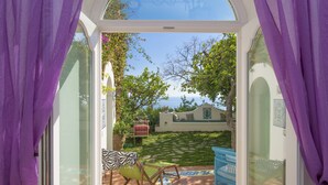A patio with a view of a garden and a building. There is a chair and a table. - Casa del Fico Dimora storica Positano (Positano)