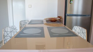 Uma cozinha moderna com geladeira de aço inoxidável, mesa de jantar com jogos americanos e cadeiras com padrão geométrico.