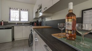 A modern kitchen with a wine bottle and glasses on the counter.