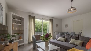 A modern living room with a grey sofa, a white coffee table, and a dining area with chairs and a table.