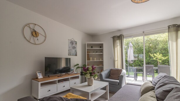 A modern living room with a flat-screen TV, a bookshelf, a coffee table, and a sofa.