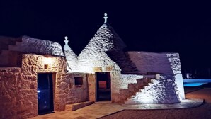 A stone building with a thatched roof, illuminated by warm lighting.