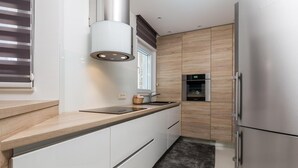 Uma cozinha moderna com forno embutido, eletrodomésticos de aço inoxidável e janela com persianas.