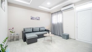 Ein modernes Wohnzimmer mit einem grauen Sofa, einem kleinen Couchtisch und einem grauen Vorhang.