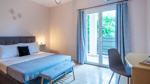 Ein Schlafzimmer mit Bett, Nachttisch, Bank, Stuhl und Blick ins Freie durch eine Schiebetür.