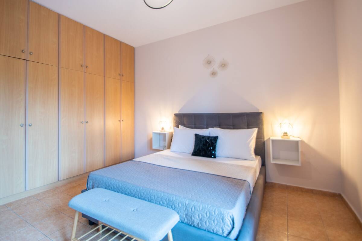 Une chambre à coucher avec un lit, des tables de chevet, un banc et une armoire en bois.