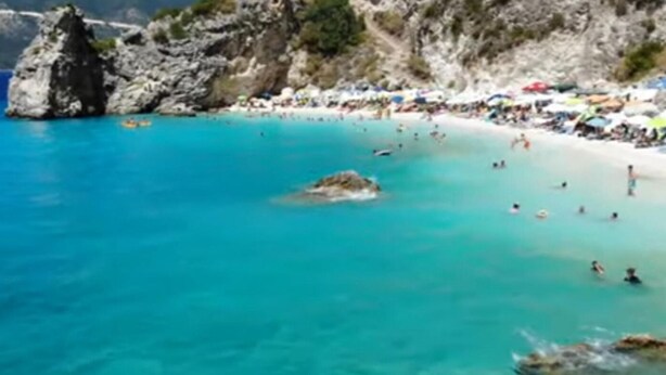 A beach with clear turquoise water, rocky outcrops, and people swimming and sunbathing. - Beautiful Modern Apartment in Lefkada, Greece (Lefkada)