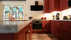 A modern kitchen with red cabinets, a built-in oven, and a microwave. - Stunning upstairs flat in The Park neighbourhood (Nottingham)